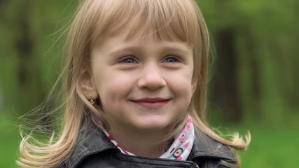 Portrait of 3 years old girl smiling on a camera. Slowly