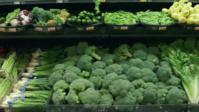 Medium tracking shot of vegetables in a grocery store