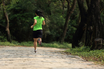 Runner athlete running on forest trail. woman fitness jogging workout wellness concept.