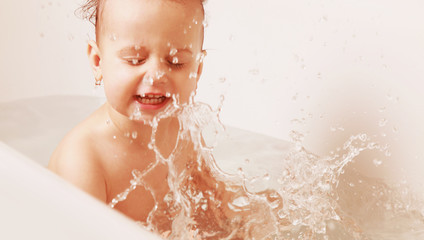 Beautiful baby girl playing with water in the bath