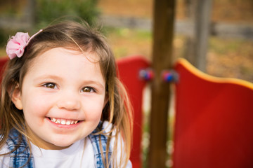 Fototapeta na wymiar Little girl smiling on a playground.