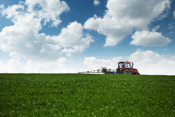 Tractor spraying wheat field with sprayer
