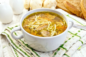 Soup with mushrooms and noodles in bowl on board