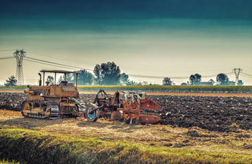 Obraz premium old tractor plowing a field