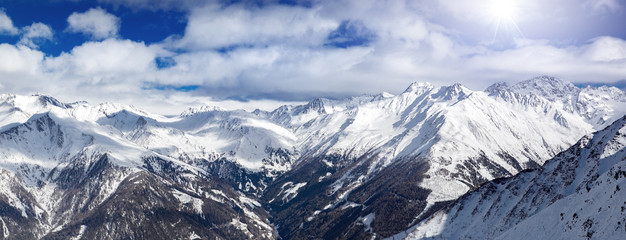 Austrian Alps winter panorama, high mountain view with beautiful clouds and sun