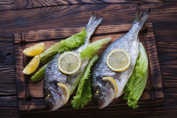 Whole baked dorado fish with salad in a rustic wooden setting