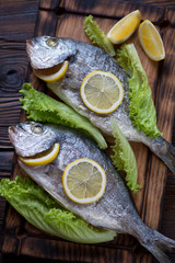 Baked sea bream with lemon and fresh green salad, above view