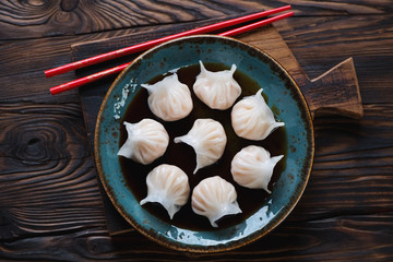 Glass plate with dim-sums in soy sauce, rustic wooden setting © Nickola_Che