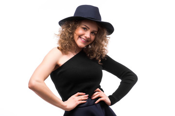 woman with curly hair in black hat and stylish elegant evening dress posing on white studio background.