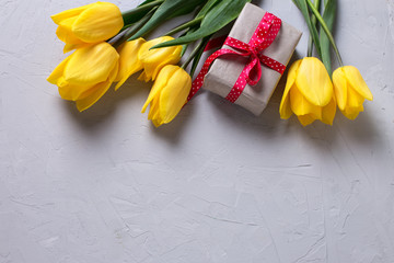 Bright yellow  spring tulips  and b wrapped box with present on