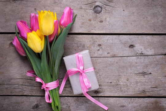 Bright yellow and pink spring tulips and box with present on vin