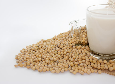 closeup is some soybeans in glass Jar and soy milk with sack background