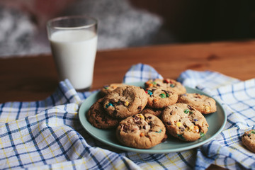 cookies on a plate and a glass of milk on a wooden table