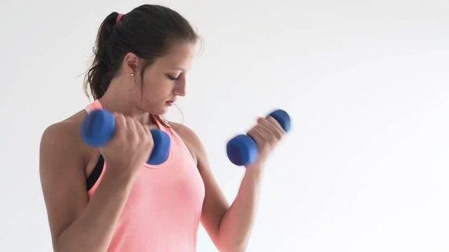 Fit young woman doing bicep curl exercises with dumb bells