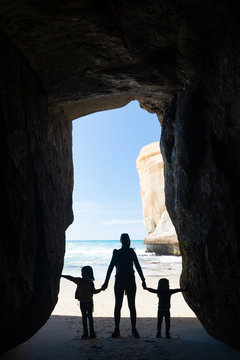 Silhouette Of Mother With Two Kids In A Cave At Tunnel Beach Near Dunedin, New Zealand