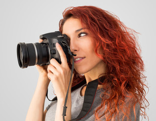 Mujer pelirroja haciendo una fotografía con una cámara reflex con un gran angular