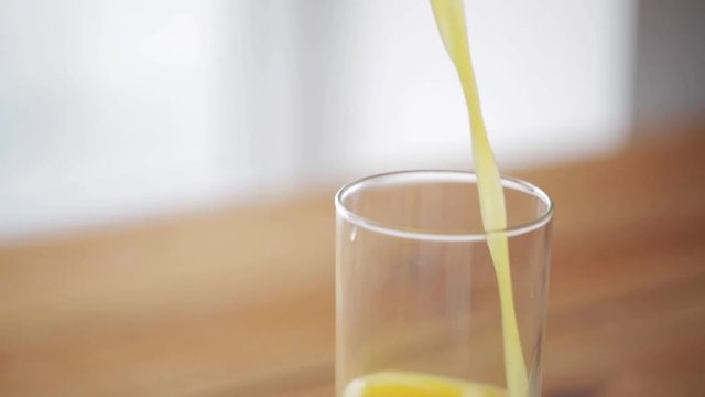 orange juice pouring into glass on wooden table
