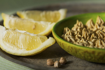 hummus, chickpea paste in the green plate with lemons close 