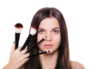 Beauty girl with makeup brushes applying nude Make-up