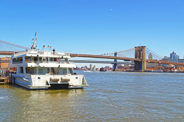 Fototapeta na wymiar Ferry and Brooklyn bridge across East River