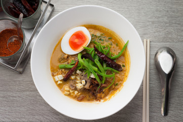 Beef noodle soup bowl with white on a wooden floor.