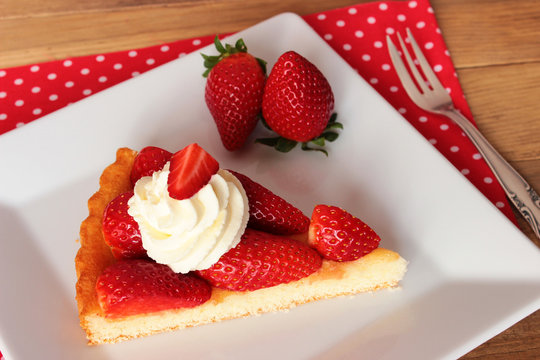 Erdbeeren, ein Stück Erdbeerkuchen mit Sahne auf weißem eckigem Teller - Strawberrycake
