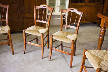 Typical italian wooden straw chairs with turned parts in a junk