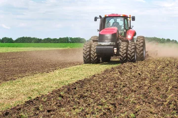 Foto op Plexiglas Modern tech red tractor plowing a green agricultural field in spring on the farm. Harvester sowing wheat. © tanger_dp