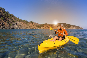 A man traveling by canoe along the coast in the summer.