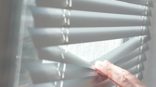 man looking through window blinds