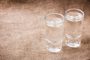 Vodka glasses on retro linen fabric texture. 