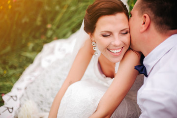 Closeup bride smiling while groom whispering compliments to her