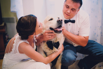 groom and bride playing with their dog labrador at home
