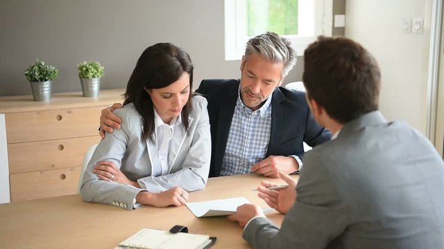 Couple in real-estate agency signing contract