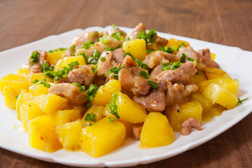 stewed chicken meat with potatoes in a plate on wooden table