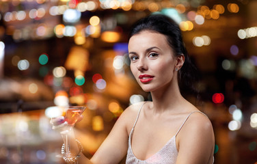 glamorous woman with cocktail at night club or bar