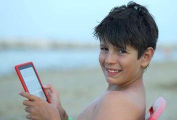 boy s reads an ebook on the beach to the sea