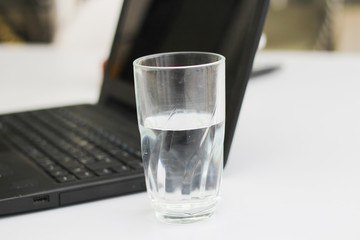 Calculator, laptop and cup of water in a workplace