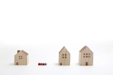 Miniature houses with alphabet blocks that spell home on white background.