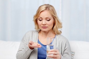 woman with medicine and water glass at home