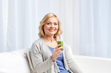 happy woman drinking green juice or shake at home