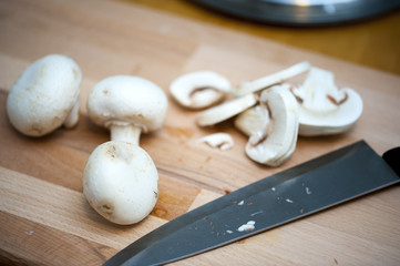 Sliced mushrooms on a chopping board with kitchen knife.
