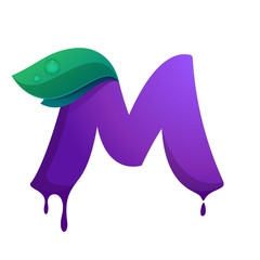 M letter with blueberry juice drops and leaves.