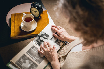 an elderly woman looks at your picture in the album made many years ago - obrazy, fototapety, plakaty
