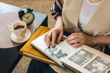 hands of an elderly woman on the photo album - obrazy, fototapety, plakaty