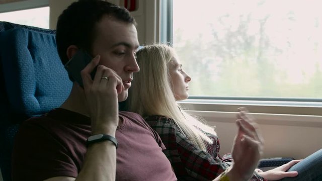Young angry man talk to somebody on a phone on a moving train