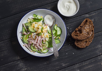 Salad with smoked turkey, cucumber and boiled egg on a dark wooden background. Healthy food
