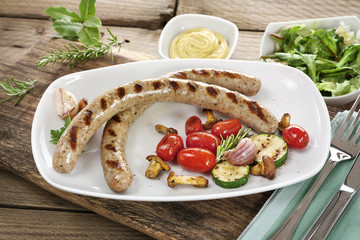 Gegrillte Bratwürste mit Beilagen auf weißem Teller