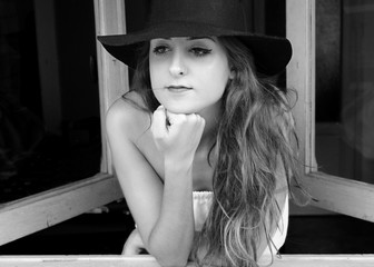 Mujer con sombrero mirando pensativa hacia la nada