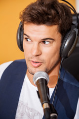 Man Singing While Wearing Headphones In Recording Studio